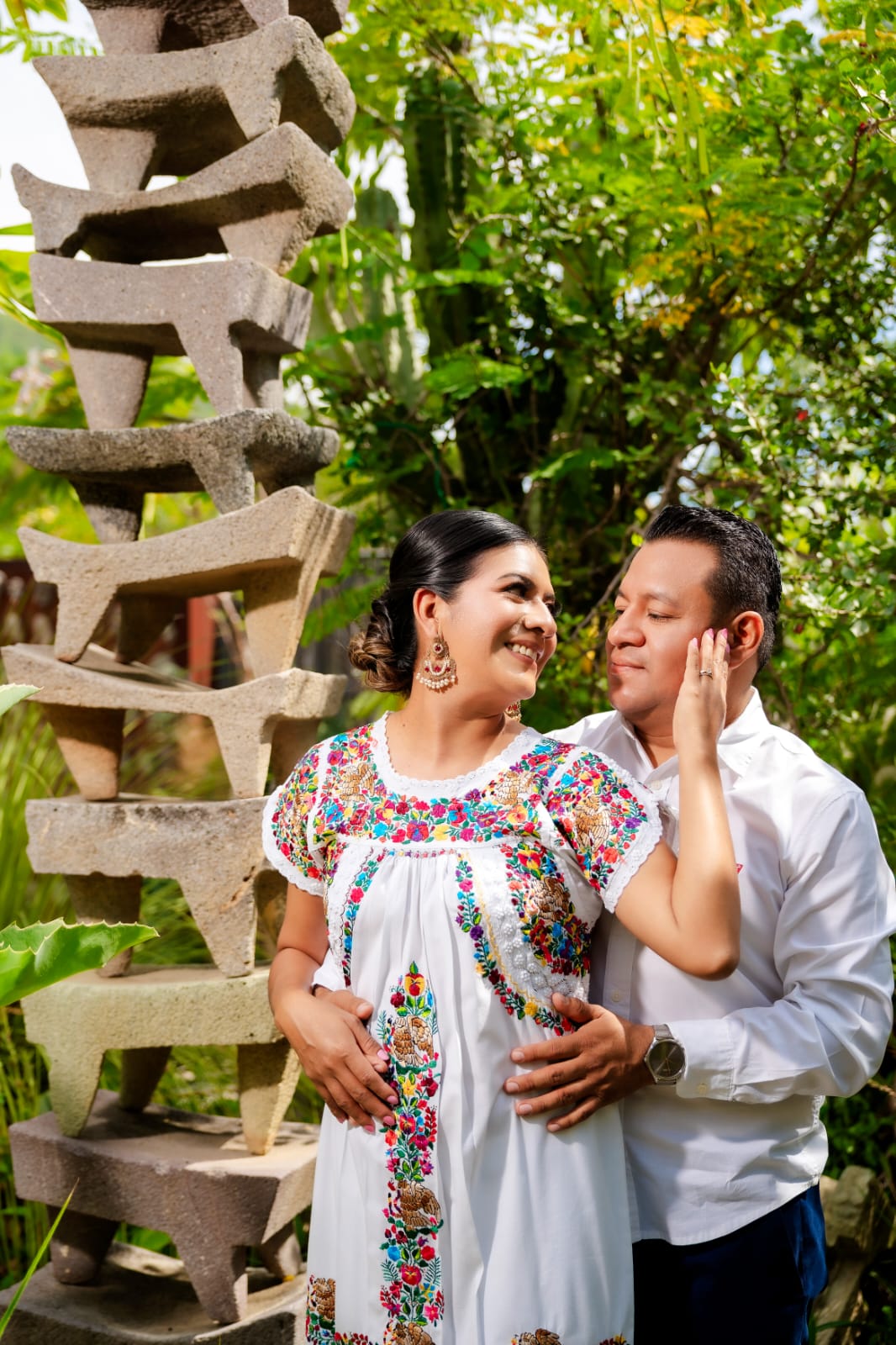 Lili y Luis, ella con la mano en su rostro, junto a la escultura de piedra